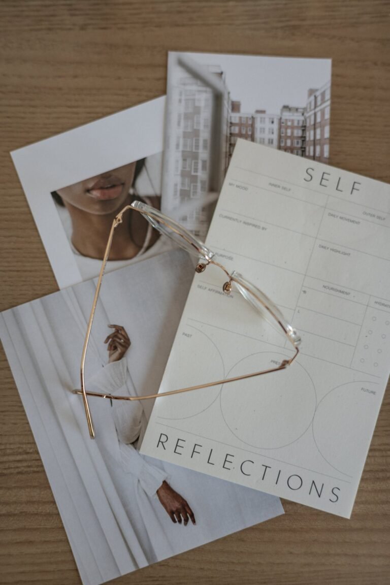 Flatlay of sunglasses, magazines and papers on a marble surface with water being poured into a glass