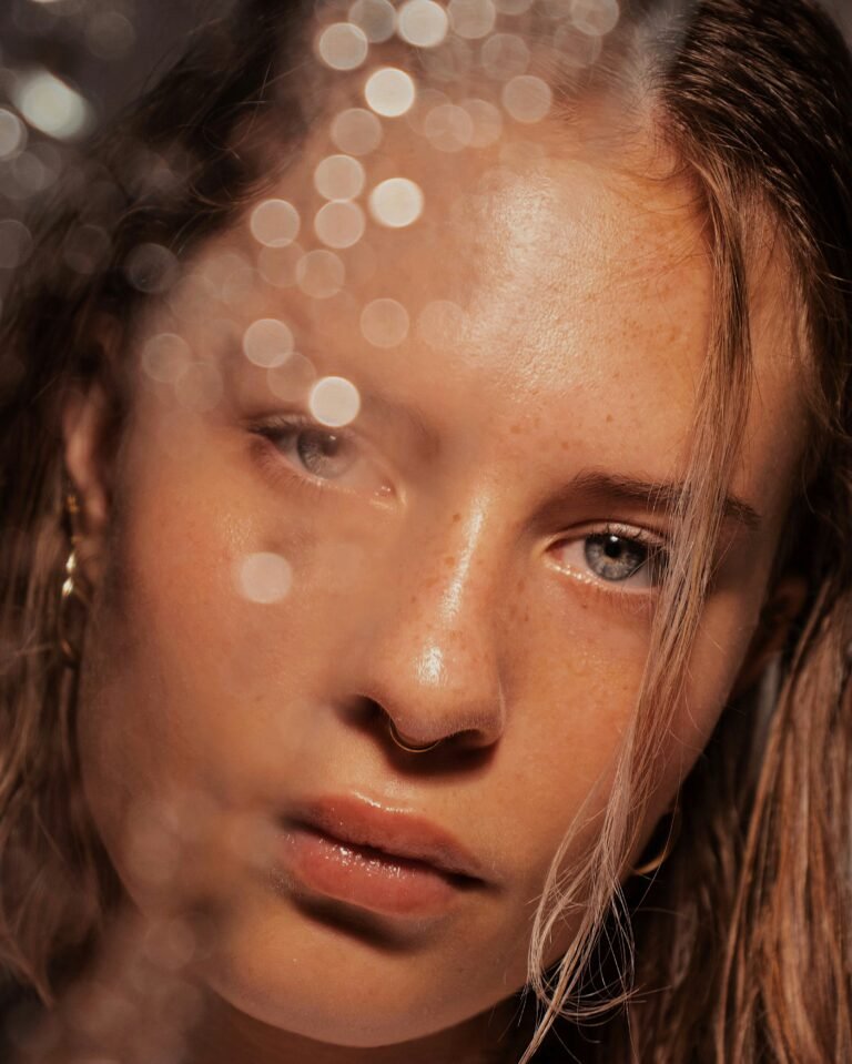 Close-up of a woman's face with freckles and water droplets on dewy skin