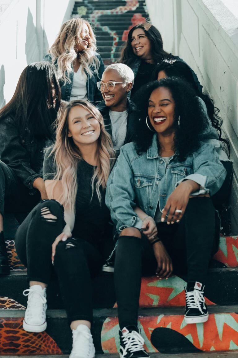 Three women in denim jackets sitting close together and laughing