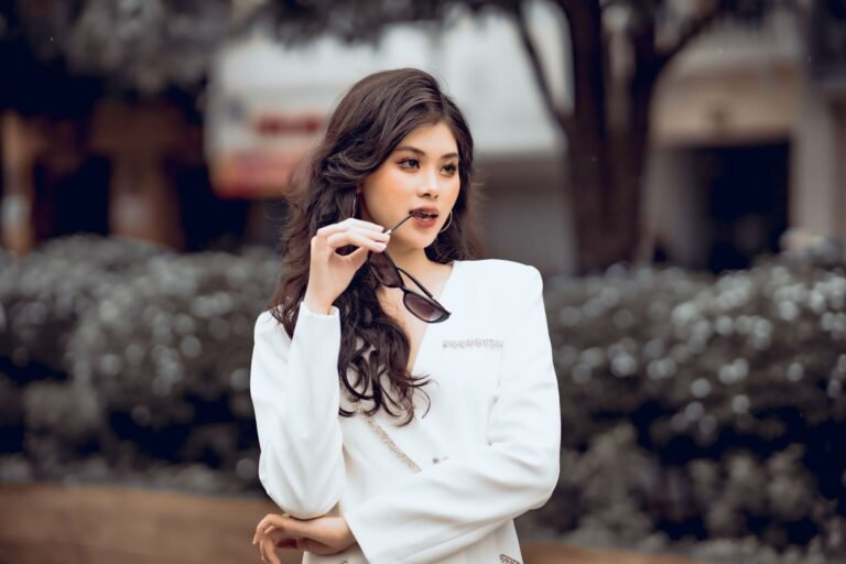 beautiful woman in white clothes biting her sunglasses